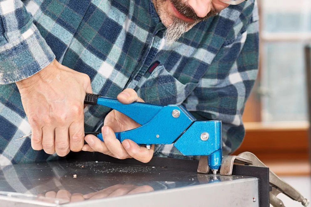 Person verwendet Nietzange an Metall